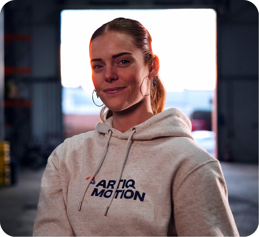 Lachende vrouw met Artiq Motion hoodie in industriële omgeving Lachende vrouw met Artiq Motion hoodie in industriële omgeving